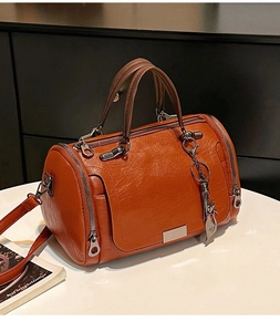 Dettaglio borsa Boston in pelle caramello con trama a grana e cerniere multiple