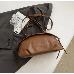Vue détaillée du sac à main en cuir marron foncé avec logo embossé et boucles en métal