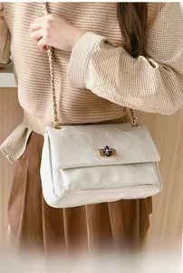 Close-up of white quilted chain bag featuring a gold rectangular twist lock and texture