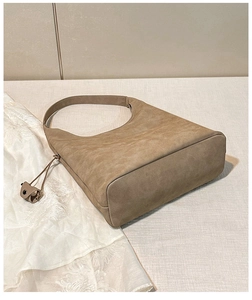Dettaglio della borsa hobo marrone grande con base ampia e ciondolo decorativo in pelle