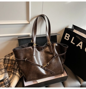 Detail of dark brown tote bag with vintage texture and crisscross strap metal buckle