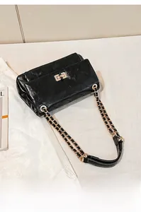 Detail of classic black quilted leather texture and gold metal chain strap on bag