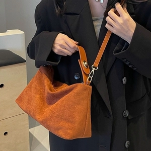 Classic caramel brown matte suede handbag with gold lock shown with a chic black suit