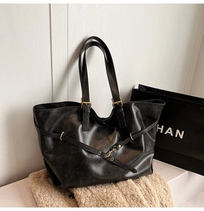Detail of black leather tote bag with gold metal hardware and textured finish
