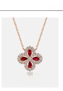 Detailed view of rose gold four-leaf clover pendant with red pear-cut gems and diamonds