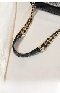 Close-up of classic gold chain strap woven with black leather for shoulder bag detail