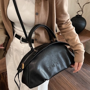 Sac bowling chic noir à texture lychee avec finitions dorées porté par un mannequin