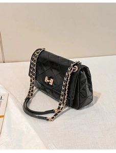 Close-up of black quilted leather texture and gold metal chain strap on a flap bag