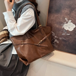 Brown leather tote bag with metal buckle detail and spacious design for daily commute