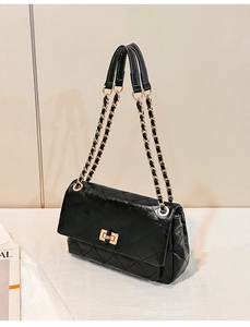 Detail of black quilted leather shoulder bag with gold twist lock and chain strap