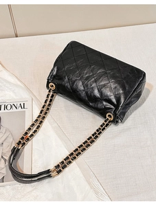 Detailed close-up of a black quilted leather chain bag with classic diamond stitching
