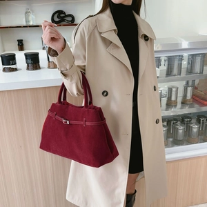 Sac fourre-tout bordeaux mat avec boucle métallique porté par un mannequin en café