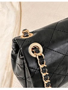 Close-up of black quilted leather with gold chain strap detail on luxury shoulder bag