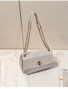Close-up of quilted chain bag featuring a gold rotating metal lock and leather strap detail
