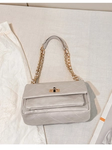 Detail of light grey quilted PU leather chain bag with golden square turn-lock closure