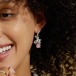 Détail de boucles d'oreilles nœud en argent avec gemme rose taillée sur le lobe