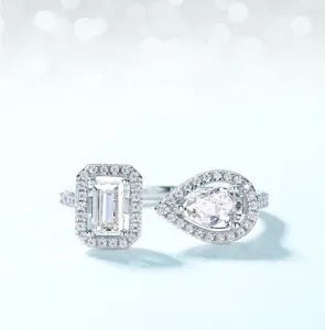 Detail of Moissanite ring with pear and emerald cut stones in halo silver setting