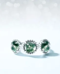 Macro shot of S925 silver ring featuring three green moss agates in six-prong setting