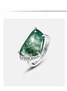 Macro detail of moss agate ring featuring feather carvings on silver metal setting