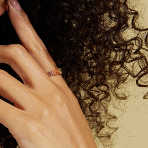 Close-up of model wearing gold gradient ring with pink and orange cubic zirconia stones