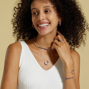 Model wearing a rainbow zircon jewelry set including necklaces and stacked bracelets
