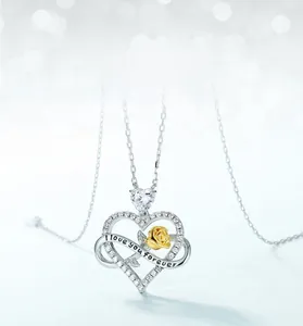Macro shot of silver heart necklace with gold rose and I love you forever engraving