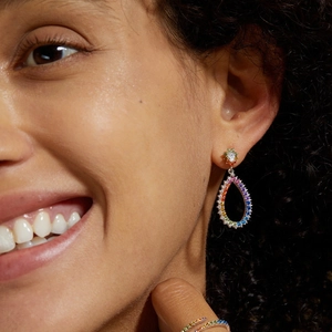 Close-up of dangling rainbow teardrop earrings set in sterling silver on model