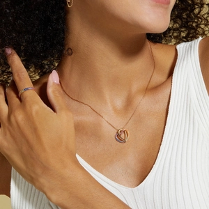 Close-up of heart pendant necklace and matching rainbow stone ring on female model