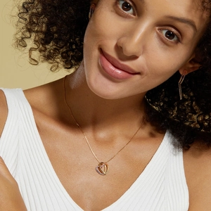 Close-up of heart pendant necklace and earrings set with colorful gradient gemstones