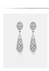 Detailed close-up of hollowed-out silver drop earrings with white zircon stone inlay