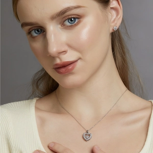 Detail van zilveren S925 hartjesketting en oorknopjes gedragen door een model