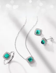 Macro shot of lab-grown emerald jewelry set with silver settings and zircon halos