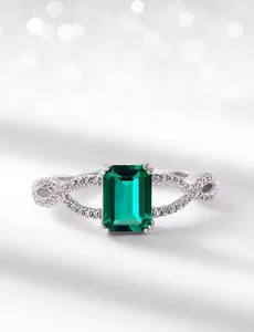 Close-up of rectangular emerald cut green gemstone on a twisted silver band with diamonds