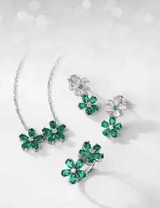 Detailed set of silver emerald floral jewelry including necklace earrings and ring