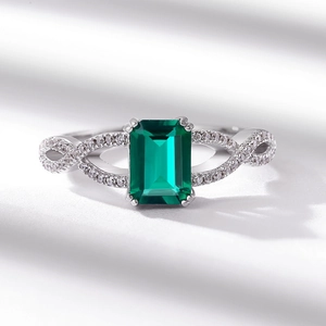 Emerald cut green gemstone ring with twisted diamond-set band in silver finish