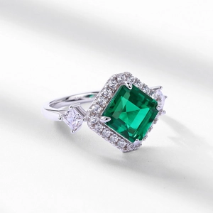 Elegant geometric emerald green ring with halo setting and side stones in silver