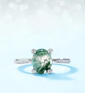 Macro view of oval moss agate ring in four-claw silver setting with pave zircons