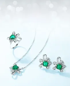 Detail of s925 silver jewelry set featuring emerald cut green gems and bow accents