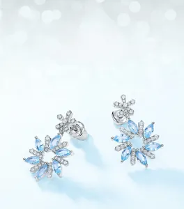 Macro view of snowflake drop earrings with sky blue gemstones and sparkling cubic zirconia