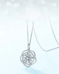 Gros plan d'un pendentif flocon de neige rotatif orné de cristaux sur un fond bleu clair