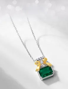 Detail of emerald cut green gemstone pendant with a golden bow and sparkling diamonds
