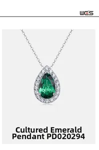 Macro detail of teardrop emerald pendant with white diamond halo on a silver chain