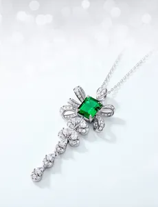 Macro shot of emerald-cut green gemstone with bow-shaped pendant and silver tassel details