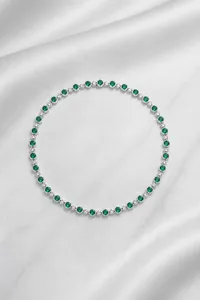 Macro shot of silver necklace NL022078 with round emerald-cut green gemstones
