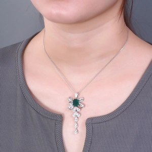 Elegant emerald pendant necklace with bow design on model with grey striped clothing