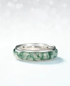 Détail d'une bague en agate mousse avec anneau intérieur argenté sur fond bleu clair