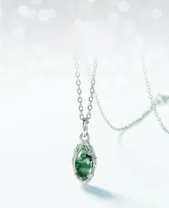 Macro detail of moss agate pendant with silver olive branch filigree and natural textures
