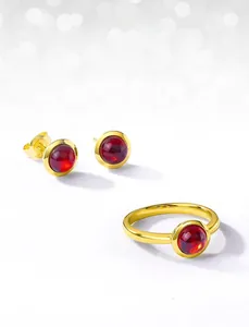 Detail of S925 gold-plated silver ring and stud earrings with red oval gemstones