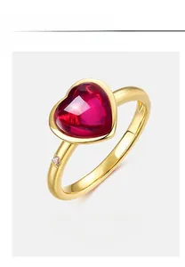 Detailed close-up of a heart-shaped ruby ring with gold band and side diamond accent