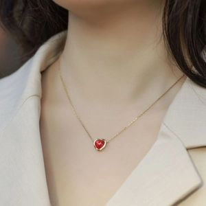 Elegante goldene Herzkette mit einem leuchtend roten Edelstein an einem weiblichen Model